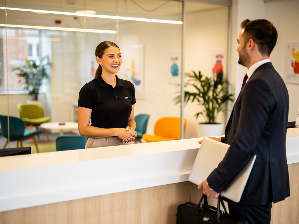 Receptionist greeting visitor in a modern UK office